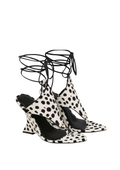 A pair of women's wedge sandals featuring a black and white cow print pattern, with black lace-up ankle straps and a low block heel, shown against a plain white background.